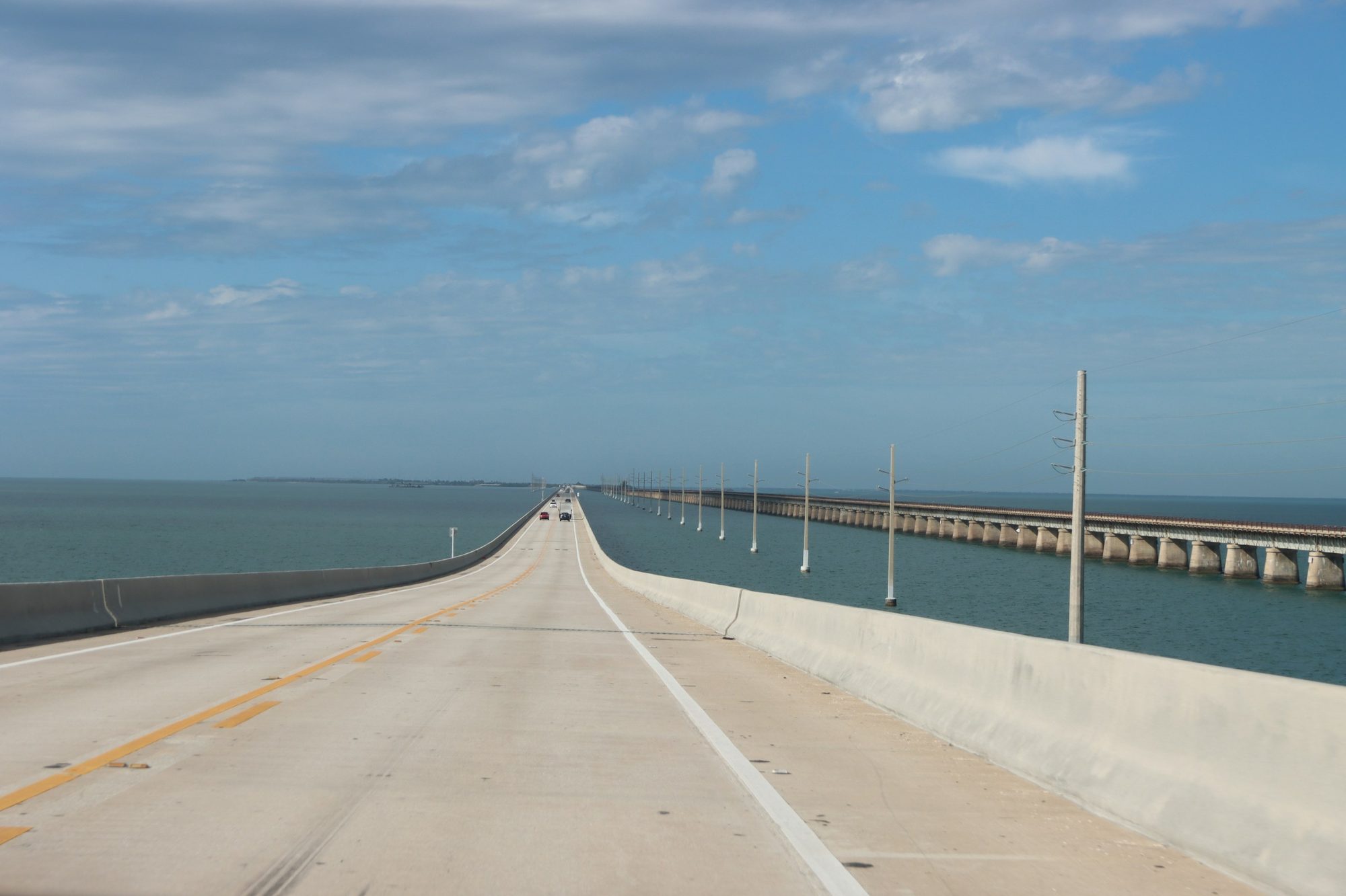 Long highway bridge running beside open water under a cloudy sky