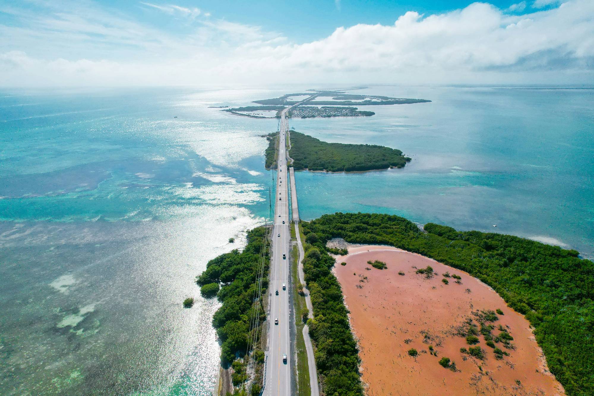 Aerial view of a coastal causeway between green islands and turquoise water